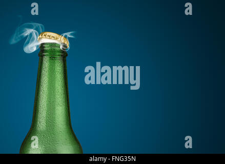Horizontale Foto von einer grünen kalte Bierflasche mit Wassertropfen und goldene Kappe öffnen auf blauem Hintergrund Stockfoto