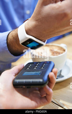 Man zahlt In Coffee-Shop mit Contactless Payment-App auf dem Smart Watch Stockfoto