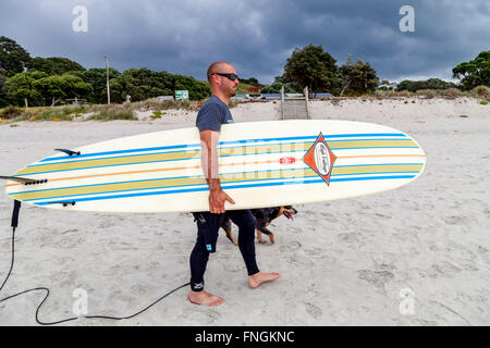 Ein junger Mann geht Surfen, waipu Cove, Waipu, Northland, Neuseeland Stockfoto