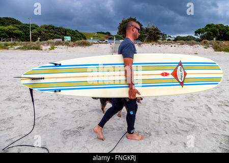 Ein junger Mann geht Surfen, waipu Cove, Waipu, Northland, Neuseeland Stockfoto