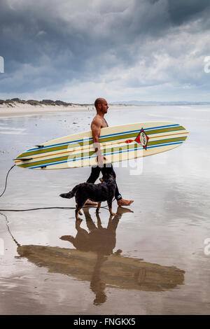 Ein junger Mann geht Surfen, waipu Cove, Waipu, Northland, Neuseeland Stockfoto