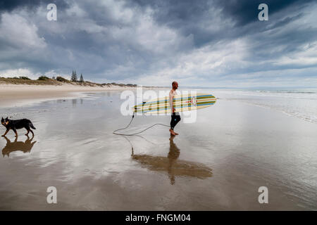 Ein junger Mann geht Surfen, waipu Cove, Waipu, Northland, Neuseeland Stockfoto