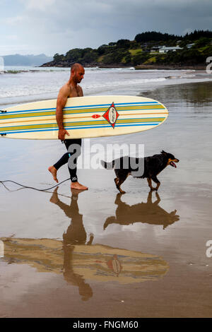 Ein junger Mann geht Surfen, waipu Cove, Waipu, Northland, Neuseeland Stockfoto