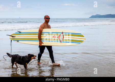 Ein junger Mann geht Surfen, waipu Cove, Waipu, Northland, Neuseeland Stockfoto