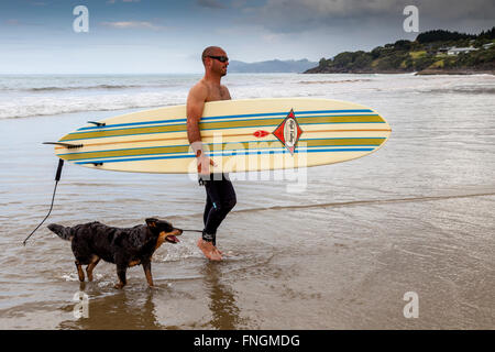 Ein junger Mann geht Surfen, waipu Cove, Waipu, Northland, Neuseeland Stockfoto