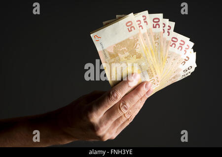 Hand, die Geld - fünfzig Euro-Banknoten auf einen dunkelgrauen Hintergrund isoliert Stockfoto