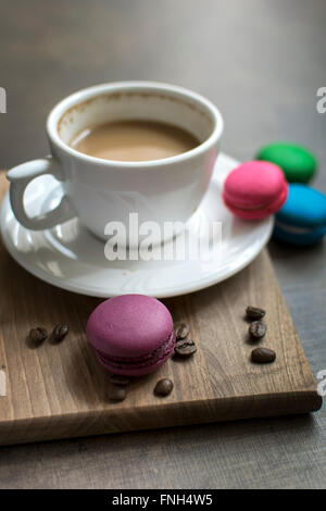 Bunte Makronen und Kaffee auf hölzernen Hintergrund, Nahaufnahme Stockfoto