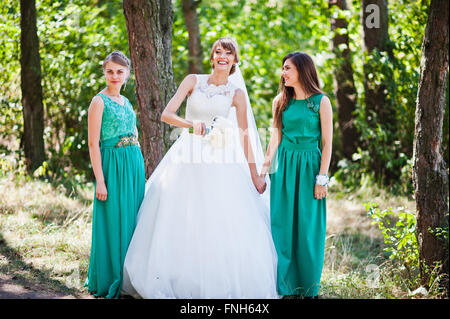 Niedliche Braut mit zwei Brautjungfern auf grünen Samtkleid Stockfoto