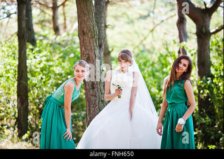 Niedliche Braut mit zwei Brautjungfern auf grünen Samtkleid Stockfoto