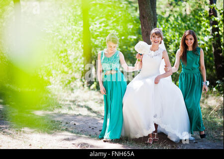 Niedliche Braut mit zwei Brautjungfern auf grünen Samtkleid Stockfoto