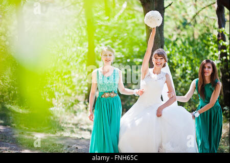 Niedliche Braut mit zwei Brautjungfern auf grünen Samtkleid Stockfoto