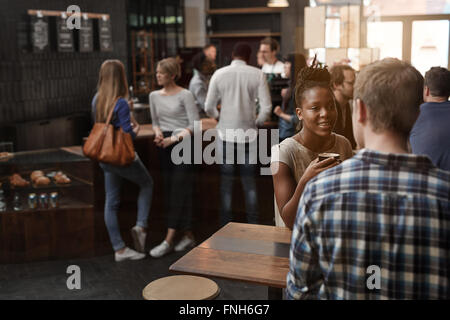 Afrikanische Frau am Tisch in einem anstrengenden modernen Café Stockfoto