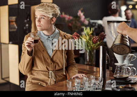 Trendige junge Frau Tagträumen in einem Café mit Kaffee Stockfoto