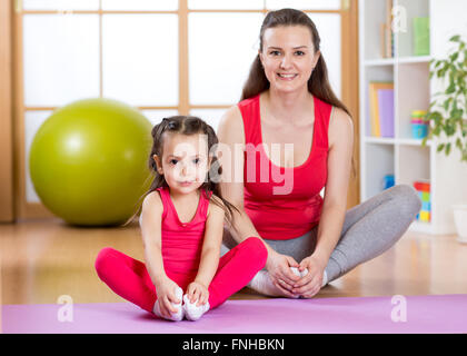 Junge Mutter mit Töchterchen Training im Fitness-Studio zu Hause Stockfoto