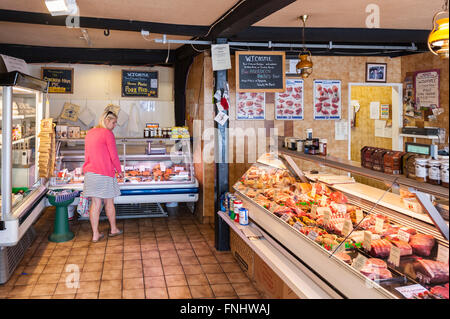 Eine Frau in ihr 30 shopping in einen Metzger Shop Shop im Vereinigten Königreich Stockfoto