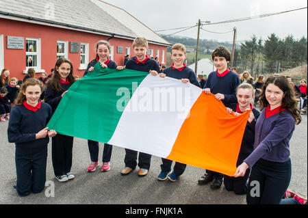 Durrus, Irland. 15. März 2016. Schülerinnen und Schüler Aisling Lager; Niamh Bignall; Rebecca Harrington; Luke Daly; James Mallon; Eoin Lager; Erica Ross und Jessica O'Driscoll zeigen die irische Trikolore vor der Anhebung der Flagge an Carrigboy National School, Durrus, am Tag der Verkündigung zur Erinnerung an die Ereignisse des Jahres 1916 stattfand. Bildnachweis: Andy Gibson/Alamy Live-Nachrichten. Stockfoto
