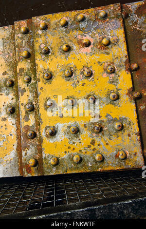 Grunge Hintergrundbild von verwitterten Metalloberfläche mit gelber Farbe und Nieten und Netz Stockfoto