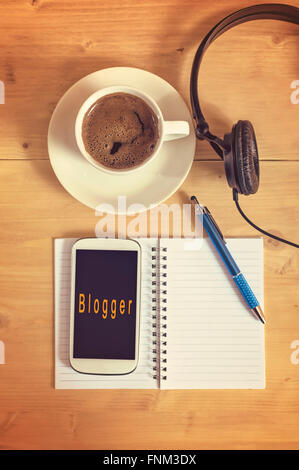 Smart phone mit Kopfhörer, Notebook, Bleistift, Kaffeetasse auf Holztisch, Blogger-Konzept. Selektiven Fokus. Stockfoto