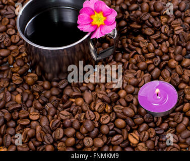 lila Kerze und Stahl Tasse Kaffee im Kaffeekörner Stockfoto