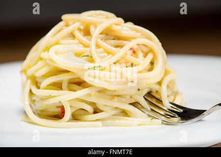 Spaghetti mit Knoblauch, Öl und Peperoni mit Petersilie und Gabel am Tisch Stockfoto