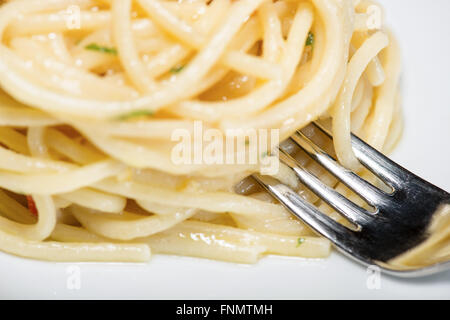 Spaghetti mit Knoblauch, Öl und Peperoni mit Petersilie und Gabel am Tisch Stockfoto