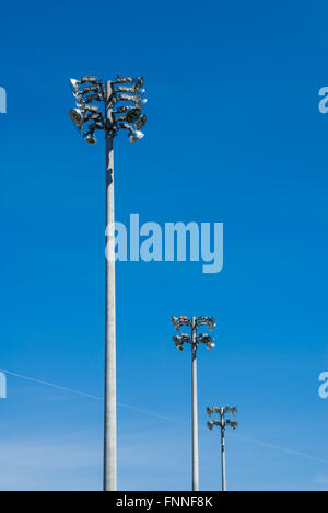 Reihe von drei industriellen Stadion Arbeitsscheinwerfer Türmen auf klaren blauen Himmel. Stockfoto