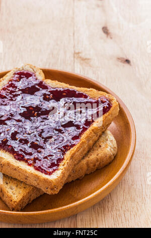 Nahaufnahme Schuss Toast mit Marmelade in hölzernen Platte Holztisch, selektiven Fokus Stockfoto