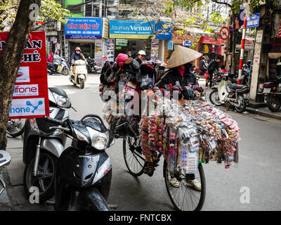Vietnamesische Frauen drücken Sie Ihre Fahrräder mit, ihre Waren zu verkaufen Stockfoto