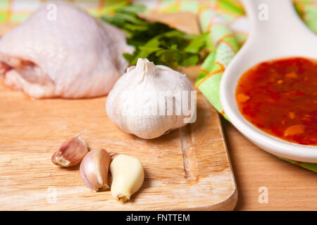 Rohe Hähnchenschenkel mit Gemüse und Gewürzen auf ein Schneidebrett Stockfoto
