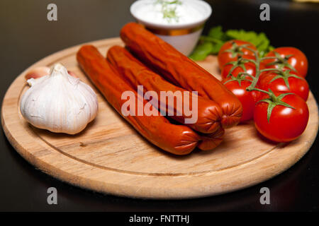 Jagd-Würstchen mit Gemüse und Sauce auf ein Schneidebrett auf Stockfoto