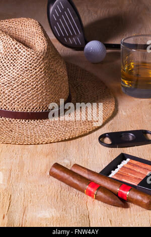 Siesta - Zigarre, Strohhut, Scotch Whisky und Golf-Fahrer auf einem Holztisch Stockfoto