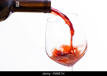 Wein aus einer Flasche in ein Glas Wein auf einem weißen Hintergrund gegossen Stockfoto
