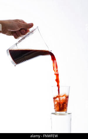 Trinken aus einem Krug in ein Glas gegossen, auf weißem Hintergrund Stockfoto