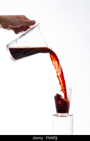 Trinken Sie, kräftig gegossen aus einer Karaffe, überfüllt, spritzt aus einem Glas auf weißem Hintergrund Stockfoto