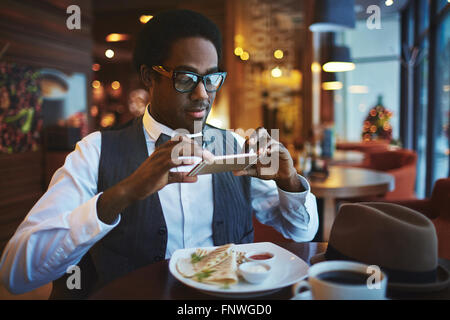 Eleganter junger Mann, Foto von Essen auf seinem Teller im café Stockfoto