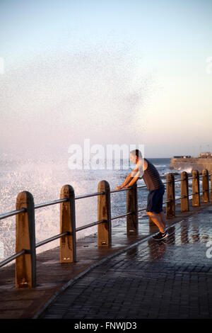 Wellen-Spray über Menschen auf der Sea Point Promenade in Kapstadt - Südafrika Stockfoto