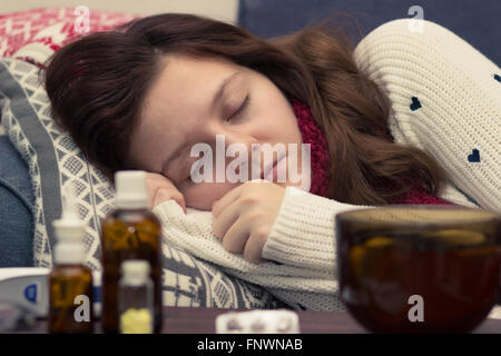 kranke Frau im Bett neben Tabletten und Drogen Stockfoto