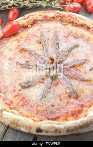 Sardellen und Tomaten Pizza auf Holztisch Stockfoto