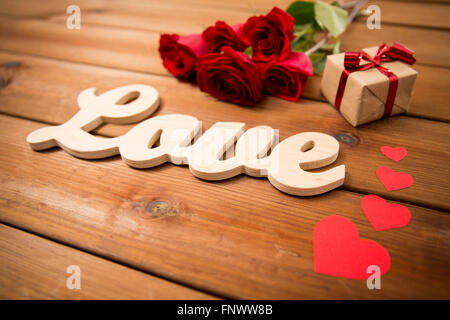 Nahaufnahme von Geschenk, Wort Liebe, rote Rosen und Herzen Stockfoto