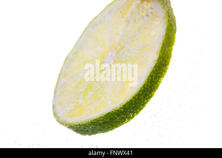 Limettenscheibe fallen oder Eintauchen in Wasser Stockfoto