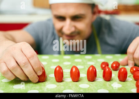 Koch, herumalbern, Cherry-Tomaten in Reihen anordnen Stockfoto