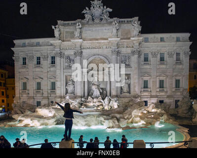 29.02.2016. Das Trevi Wasser Brunnen, Rom bei Nacht mit Touristen. Eine junge Frau steht auf einer Säule am Trevi-Brunnen Stockfoto