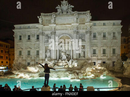 29.02.2016. Das Trevi Wasser Brunnen, Rom bei Nacht mit Touristen. Eine junge Frau steht auf einer Säule am Trevi-Brunnen Stockfoto