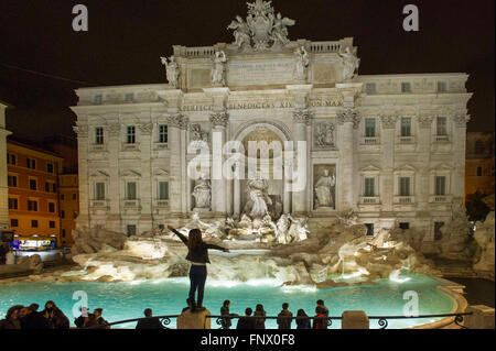 29.02.2016. Das Trevi Wasser Brunnen, Rom bei Nacht mit Touristen. Eine junge Frau steht auf einer Säule am Trevi-Brunnen Stockfoto