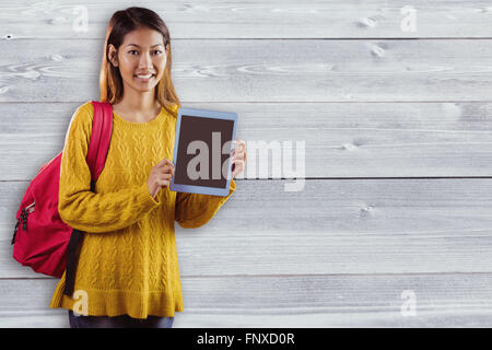 Zusammengesetztes Bild des Lächelns asiatische Studentin zeigt tablet Stockfoto