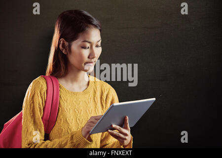 Zusammengesetztes Bild an fokussierte asiatische Studentin mit tablet Stockfoto