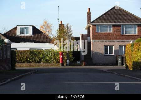 Straßenszene mit Hecke und roten Briefkasten in Swindon, Großbritannien. Stockfoto