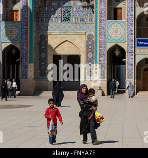 Besucher, einschließlich Familien und Tschador bekleideten Frauen, auf dem Vorplatz des Shah Cheragh Mausoleums, Shiraz, Iran Stockfoto