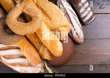 Große gemischte Brot Sortiment bestehend aus Sesam und Mohn Bagels, französisches Brot, Baguette, Brötchen und Roggen auf Holztisch Stockfoto