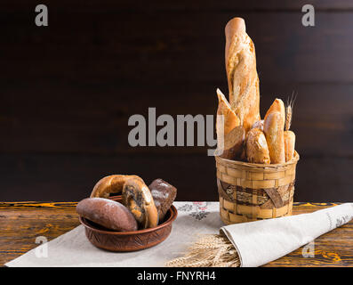 Sortierte frisches Brot und Brötchen auf dem Display in einer Bäckerei in einer rustikalen Korb und Keramik Schüssel mit textfreiraum hinter Stockfoto